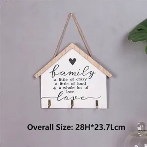 Nahaufnahme des hausförmigen Schlüsselbretts aus Holz mit Familienspruch und Haken