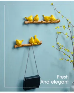 Nordic yellow resin bird wall hooks mounted on blue wall with a hanging handbag