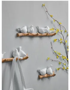 Decorative Nordic bird wall hooks mounted on a grey wall with a hanging bag detail.