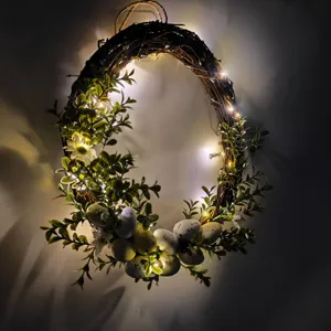 Illuminated Easter wreath with speckled eggs and spring greenery on dark background