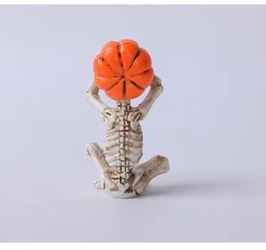 A detailed back view of a meditation skeleton figurine with a bright orange pumpkin head