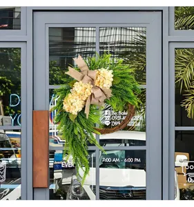 Detailed view of artificial hydrangea wreath with burlap bow on a glass shop door