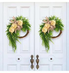 Detailed view of two farmhouse hydrangea artificial wreaths with burlap bows on white doors