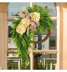 Elegant hydrangea artificial wreath with burlap bow hanging on a rustic glass door