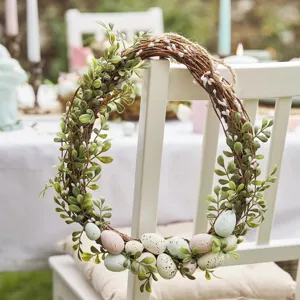 Detail of Easter wreath with speckled pastel eggs and artificial boxwood leaves on chair.