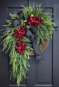 Detailed view of artificial red hydrangea wreath with green foliage and black bow