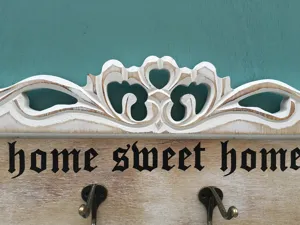 Detailansicht Vintage-Wandhaken aus Holz mit Schnitzerei und Home Sweet Home Text.