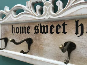 Detail eines hölzernen Wandhakens mit Schnitzereien und Home Sweet Home Text