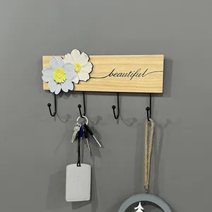 Close-up detail of a minimalist wooden wall hook rack featuring creative floral decorations and keys