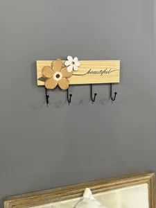Close-up detail of a minimalist wall-mounted wooden coat rack with 4 metal hooks