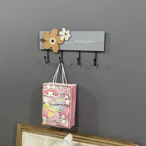 Close-up detail of a modern wooden wall-mounted coat rack with floral accents and four hooks