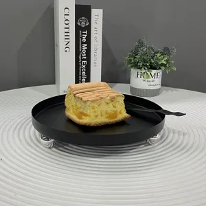 Eleganter schwarzer Metall-Dessertteller mit silbernen Kugelfüßen und einem Stück Kuchen