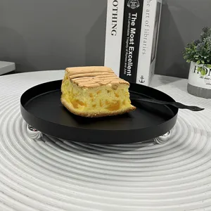 Detailansicht eines schwarzen Metall-Desserttabletts mit einem Stück Kuchen auf weiß