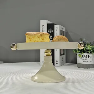 Eleganter Tortenständer aus Eisen in Creme mit goldenen Akzenten für Gebäck