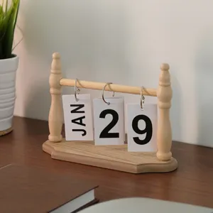 Nordic style wooden perpetual flip calendar on a desk with a green plant background.