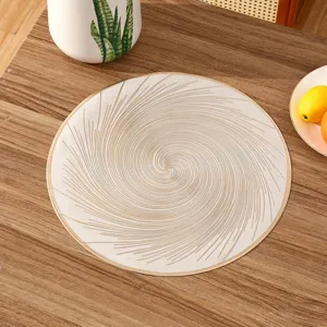 Detailed view of a circular PVC placemat with elegant gold spiral pattern on wood