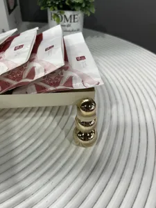Detailaufnahme eines weißen Eisen-Tabletts mit dekorativen goldenen Kugelfüßen
