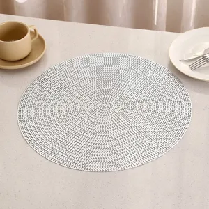Detail view of a white round PVC placemat with elegant woven texture on a table