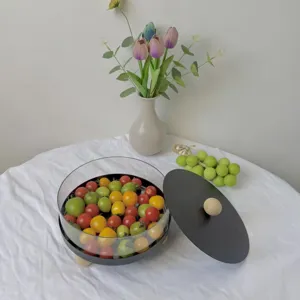Detalle del frutero redondo de acrílico con tapa negra mate y patas de madera clara