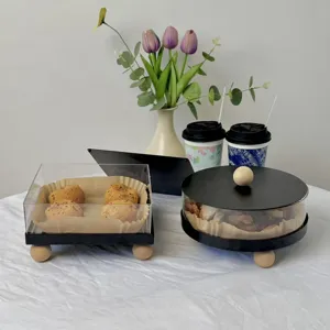 Macro view of transparent acrylic dessert display box with minimalist black base and wooden feet