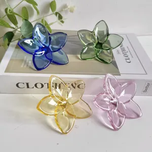 Macro view of four assorted colored crystal glass flower ornaments on a white aesthetic book