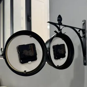 Detailed view of internal dual quartz mechanisms in a double-sided iron wall clock.
