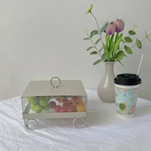 Vista detallada de la caja cuadrada de exhibición de postres con fruta en una mesa blanca