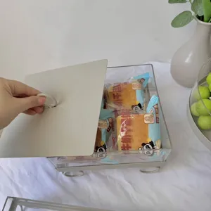 Primer plano de una mano levantando la tapa de una caja de exhibición para postres.