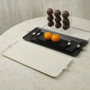 Detailansicht von minimalistischen Tabletts aus Metall für Desserts in Creme und Schwarz.