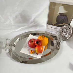 Detail view of oval stainless steel mirror tray with transparent handles and fruit