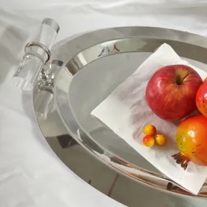 Detailed close-up of a stainless steel oval mirror tray with clear acrylic handles