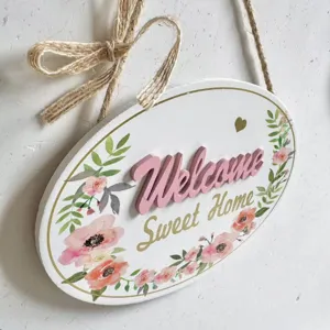 Detailed shot of oval wooden Welcome sign with pink 3D letters and floral patterns.