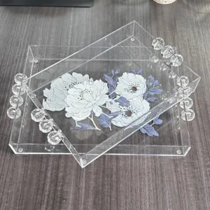 Set di due vassoi in acrilico trasparente con manici a sfera di cristallo e fiori.