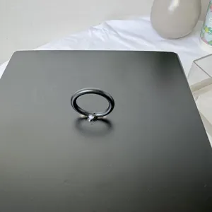 Primer plano de una tapa cuadrada negra de caja de postres con tirador de anillo circular.