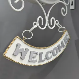 Close-up detail of vintage white wrought iron double-sided wall clock welcome sign