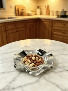 Vista detallada de un frutero de cristal ondulado con nueces en una mesa de cocina de mármol