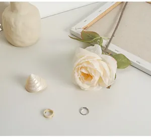 Detailed close-up of a French romantic burnt-edge cream faux rose with aesthetic props