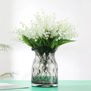 Realistische kunstmatige lelietjes-van-dalen bloemen in een stijlvolle grijze glazen vaas