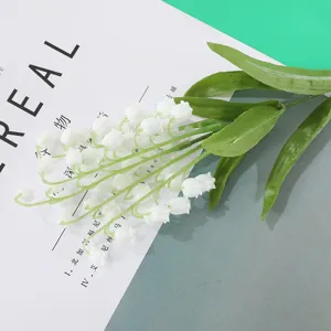 Detailopname van realistische kunstmatige witte lelietje-van-dalen met groene bladeren