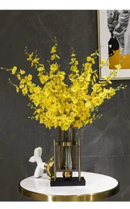 Detailansicht gelber tanzender Orchideen-Seidenblumen in einer luxuriösen Glasvase.