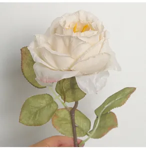 Close-up of a French style artificial cream rose with elegant burnt edges and green leaves