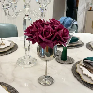 Eleganter künstlicher magentafarbener Rosenstrauß in einer silbernen Kelchvase auf Marmor.