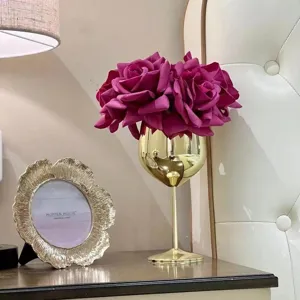 Nahaufnahme von magentafarbenen Kunstrosen in einer goldenen Vase für Wohndekoration