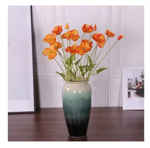 Detalle de amapolas artificiales naranjas en un jarrón de cerámica azul decorativo