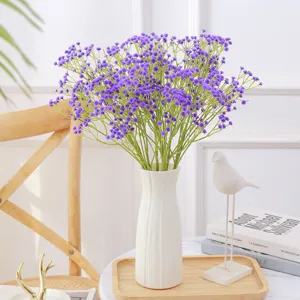 Vista detallada de flores de gypsophila artificiales púrpuras en un moderno jarrón blanco