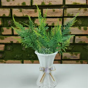 Vista detallada de helecho artificial verde en un jarrón decorativo blanco tejido