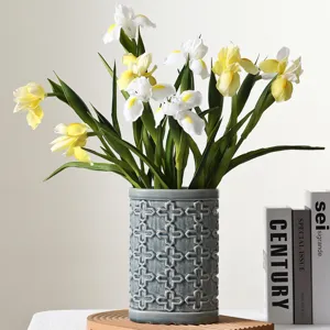 Close-up of realistic white and yellow PU iris flowers in a textured ceramic vase