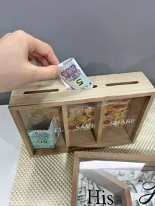 Detailansicht einer Hand, die Bargeld in eine hölzerne Sparkasse mit 3 Fächern legt
