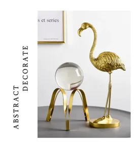 Modern luxury crystal ball on golden tripod stand with elegant golden flamingo