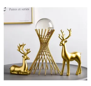 Elegant golden deer figurines with a crystal ball set on a minimalist gold wire stand